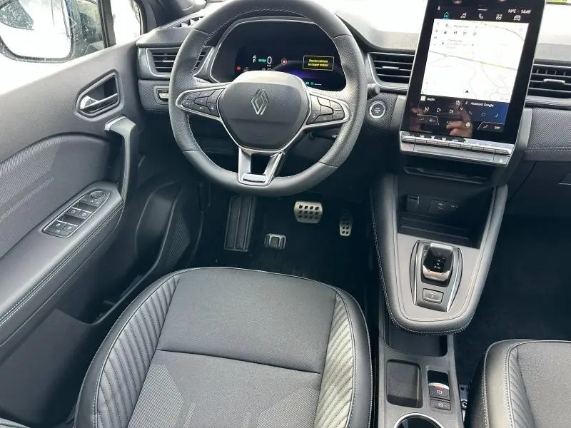 Vue intérieure du poste de conduite du Renault Captur 2026 hybride, avec volant multifonction et écran tactile vertical.