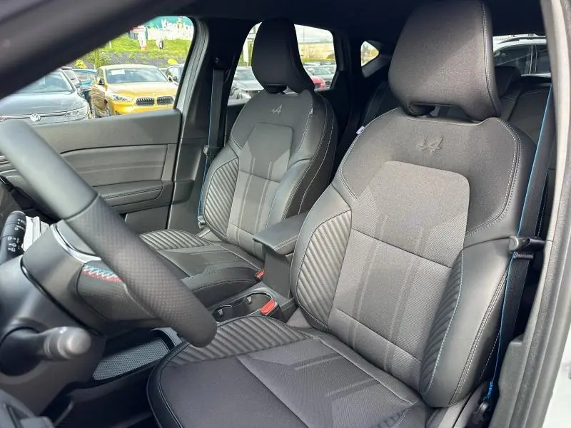 Vue intérieure de face des sièges avant gris foncé du Renault Captur 2026 esprit Alpine avec surpiqûres bleues et logo Alpine brodé.