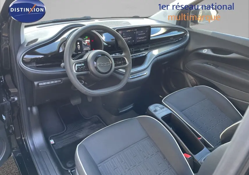 Intérieur noir de la Fiat 500 électrique 2023 vu de côté conducteur, avec tableau de bord moderne et sièges tissu.