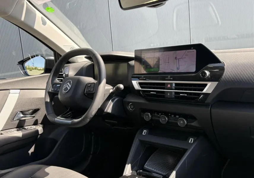 Vue intérieure côté conducteur de la Citroën C4 Hybrid 145 e-DSC6 Max avec tableau de bord noir et écran tactile GPS.