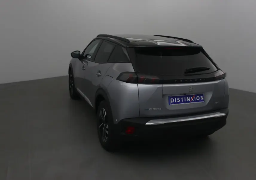 Vue 3/4 arrière d'un Peugeot 2008 électrique gris Artense avec toit noir, feux arrière LED et jantes noires.