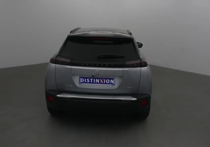 Vue arrière d'un Peugeot 2008 électrique gris Artense avec toit noir et feux arrière caractéristiques en forme de griffes.