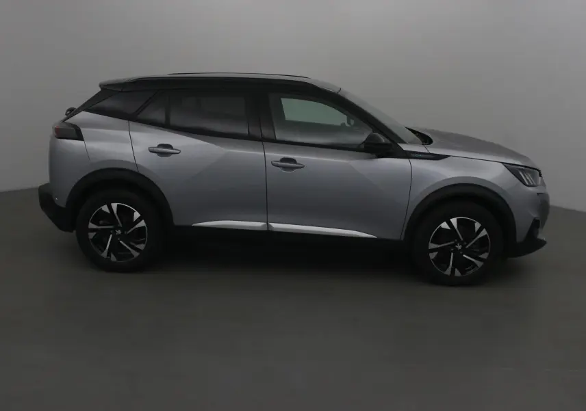 Profil côté gauche du Peugeot 2008 électrique 2022 en gris Artense avec toit noir et jantes noires.