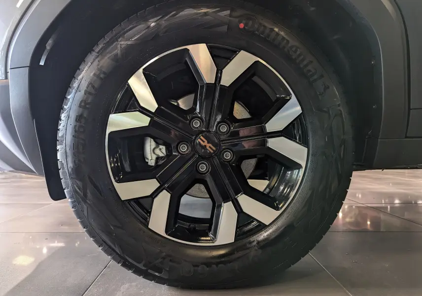 Gros plan sur la roue avant droite du Dacia Duster 2025 gris schiste avec jante alliage noire et argentée.