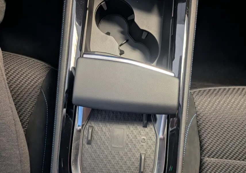 Vue plongeante sur la console centrale noire du Renault Espace VI hybride avec chargeur à induction et porte-gobelets.