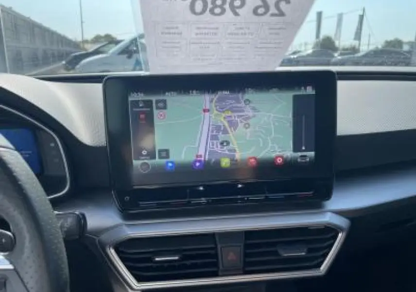 Vue intérieure du tableau de bord du SEAT Leon IV blanc Nevada, mettant en valeur l'écran tactile de navigation central.