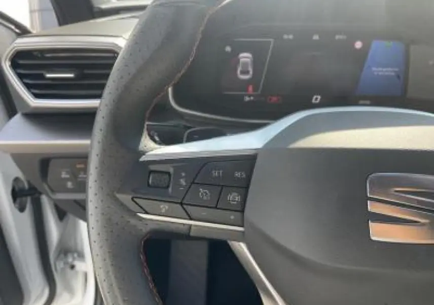 Volant perforé avec surpiqûres rouges et logo SEAT, tableau de bord digital du SEAT Leon blanc Nevada 2024.