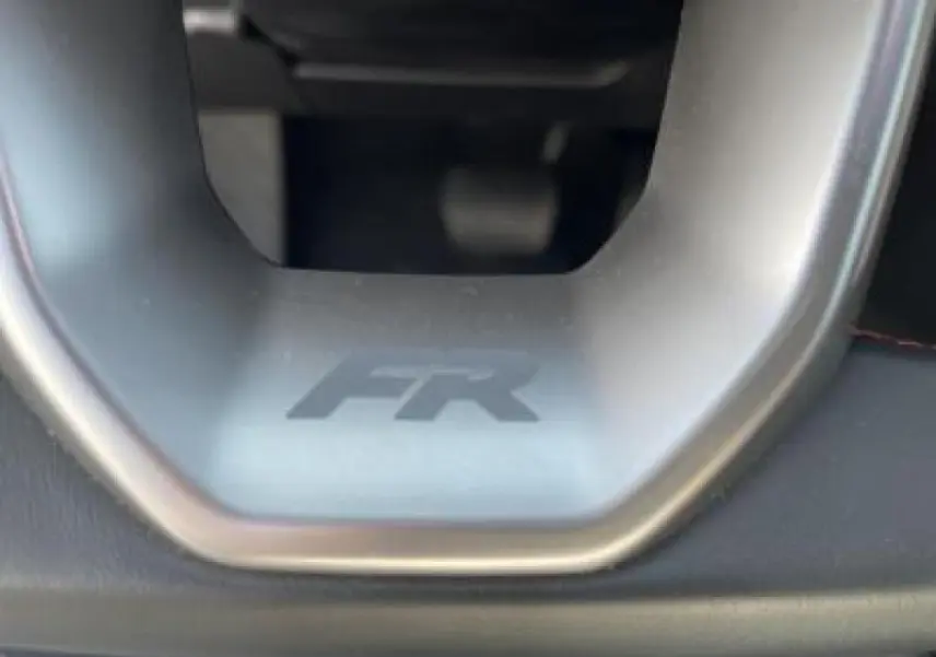 Gros plan sur le volant avec logo FR de la SEAT LEON IV blanc Nevada, mettant en valeur la finition sportive.