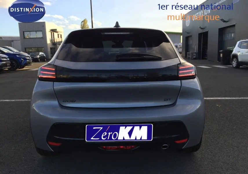 Vue arrière d'une Peugeot 208 GT gris Artense métal avec feux arrière LED allumés sur un parking extérieur.