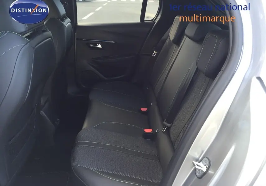Vue intérieure côté arrière droit montrant les sièges arrière noirs avec surpiqûres vertes d'une Peugeot 208 gris Artense 2025.