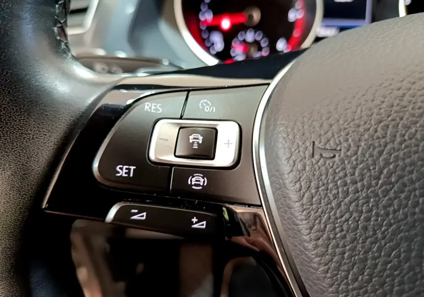 Gros plan sur les commandes de régulateur de vitesse au volant cuir noir du Volkswagen Tiguan 2020.