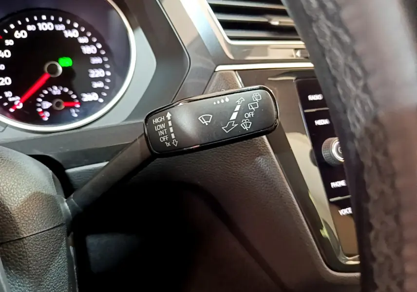 Gros plan sur la commande d'essuie-glace à gauche du volant dans l'habitacle du Volkswagen Tiguan gris clair 2020.