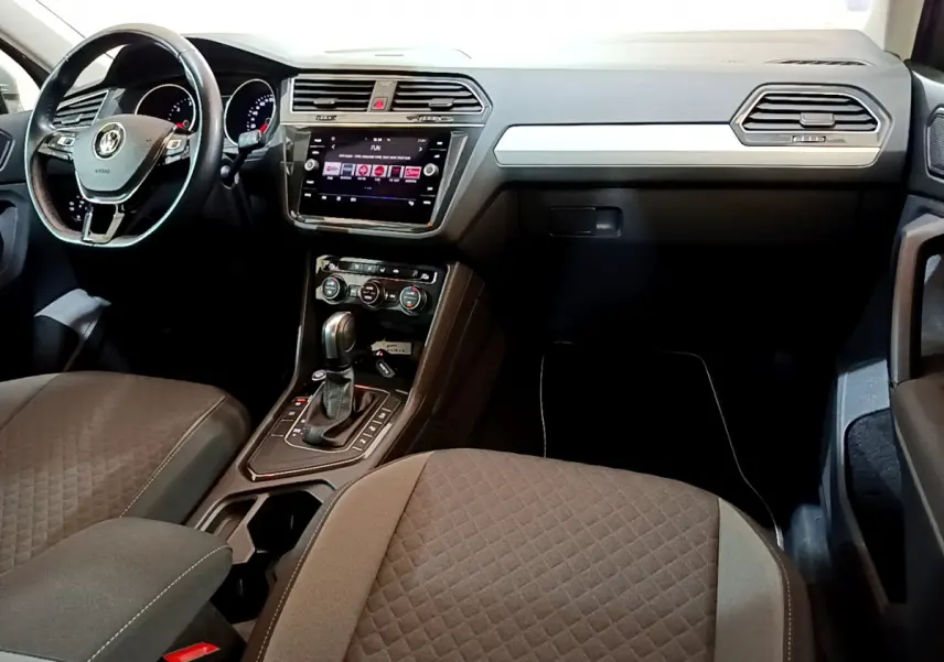 Intérieur du Volkswagen Tiguan 2020 vu côté passager, tableau de bord noir avec écran tactile et volant cuir.