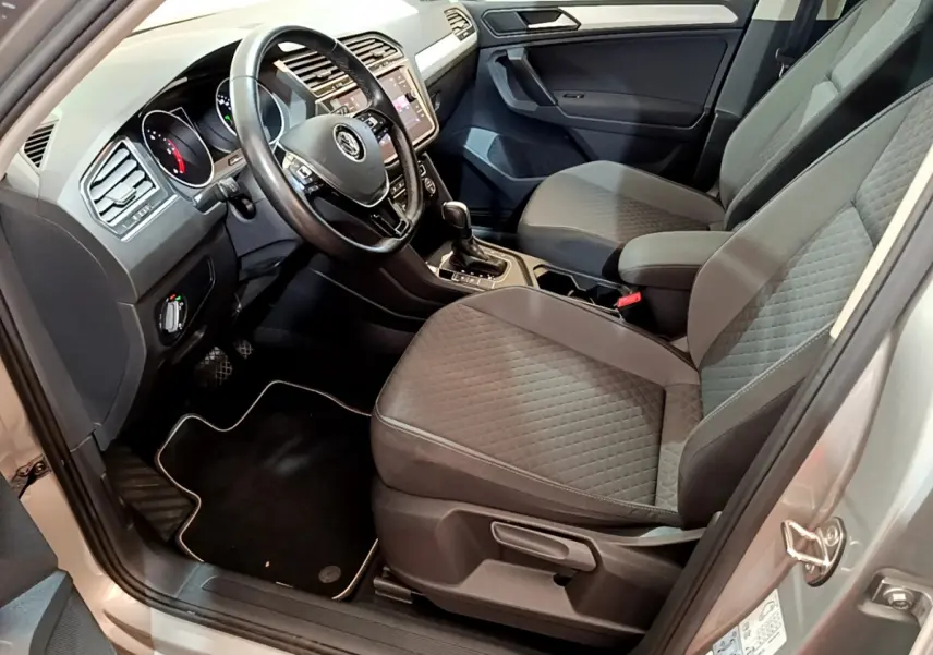 Intérieur avant droit du Volkswagen Tiguan gris clair 2020, sièges tissu gris et tableau de bord avec écran tactile.