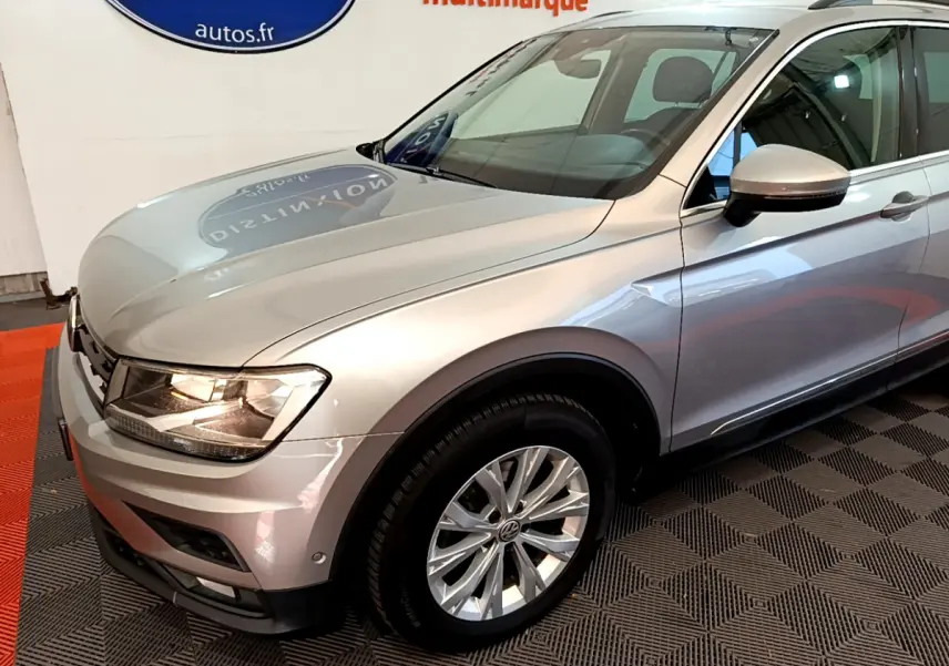 Vue 3/4 avant droit d'un Volkswagen Tiguan gris clair avec jantes alliage et rétroviseurs assortis.