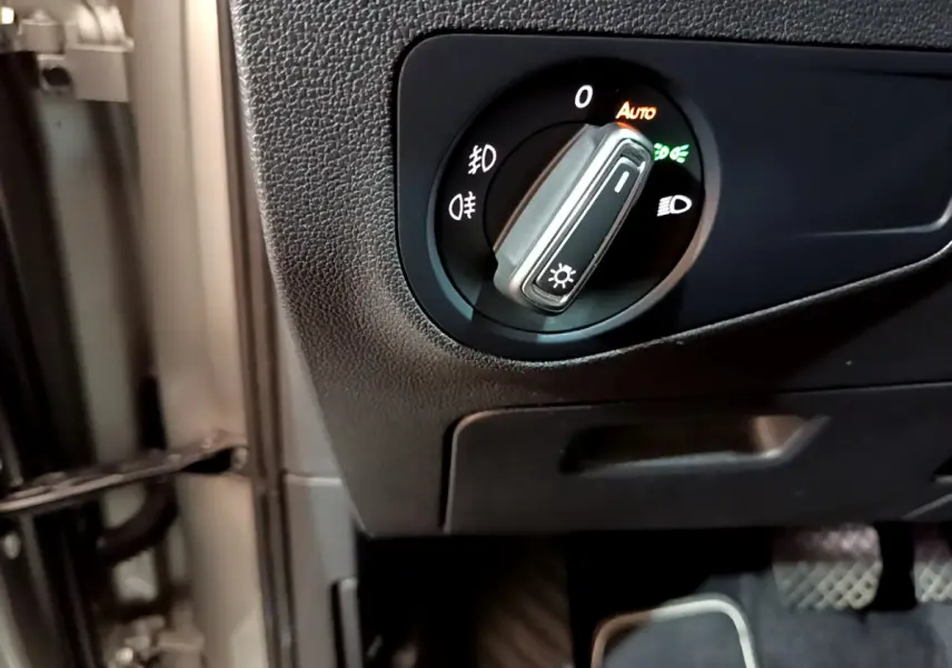 Gros plan sur le sélecteur de phares noir dans l'habitacle du Volkswagen Tiguan gris clair 2020.