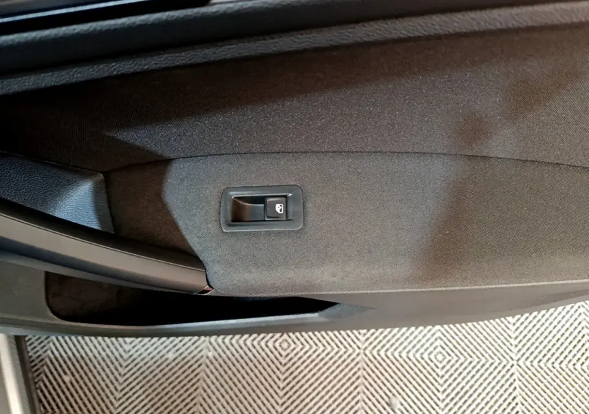 Bouton de verrouillage des portes sur la garniture intérieure noire de la porte côté gauche du Volkswagen Tiguan gris clair.