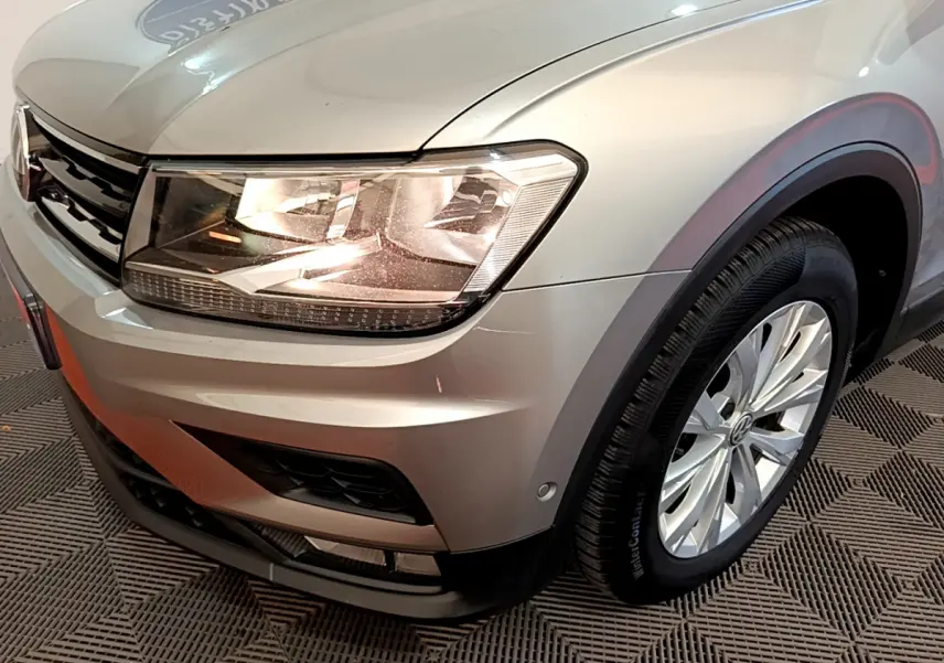 Vue 3/4 avant droit d'un Volkswagen Tiguan gris clair mettant en valeur son phare et sa roue avant.