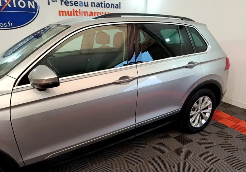 Vue latérale côté gauche d'un Volkswagen Tiguan gris clair 2020 avec rétroviseur et jantes visibles.