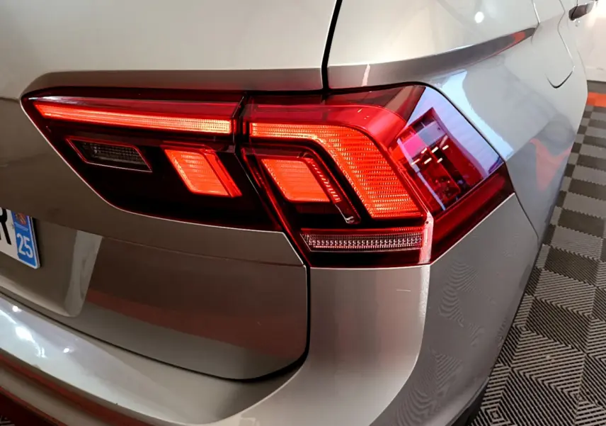 Gros plan sur le feu arrière droit d’un Volkswagen Tiguan gris clair 2020, avec détails lumineux nets et carrosserie brillante.