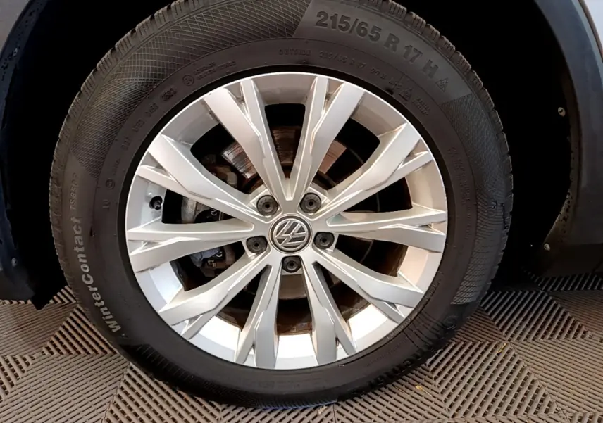 Gros plan sur la jante alliage argentée et pneu hiver du Volkswagen Tiguan gris clair, côté avant droit.