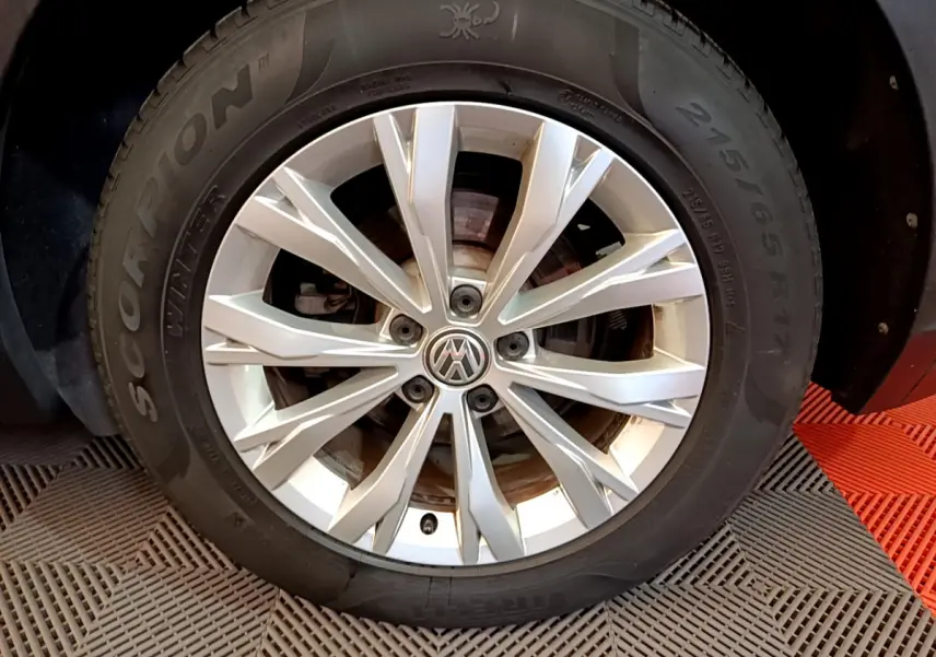 Gros plan sur la roue avant droite du Volkswagen Tiguan gris clair, avec jante alliage et pneu hiver Pirelli.