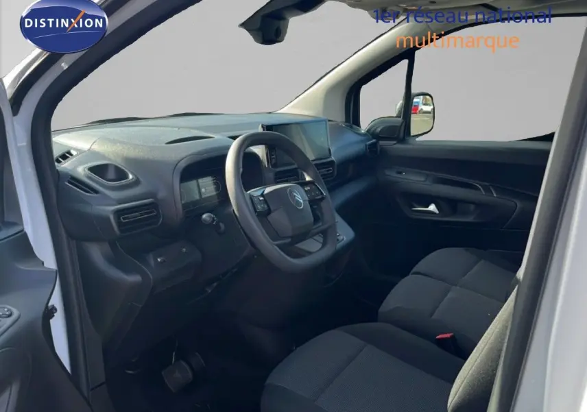 Vue intérieure côté conducteur du Citroën Berlingo blanc icy 2025, montrant le tableau de bord et les sièges tissu noirs.
