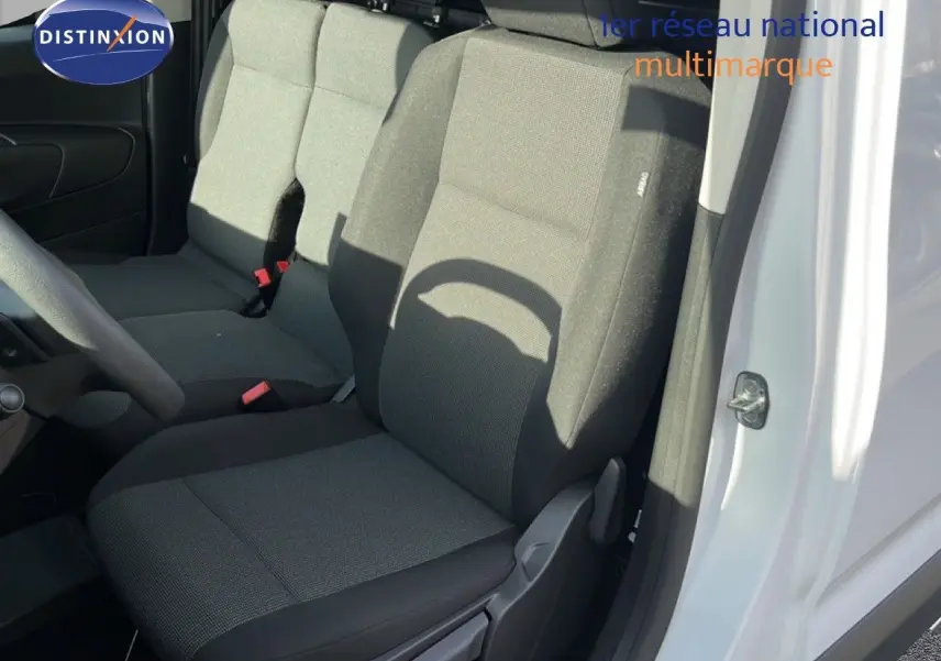 Vue intérieure côté conducteur du Citroën Berlingo blanc Icy 2025, sièges tissu gris foncé avec airbag latéral.