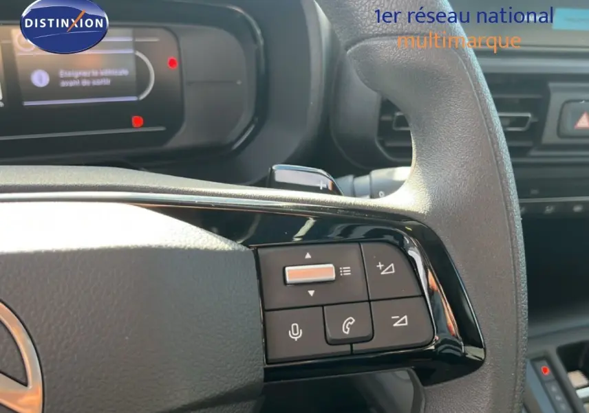 Gros plan sur le volant multifonction noir du Citroën Berlingo 2025, avec commandes audio et téléphone visibles.