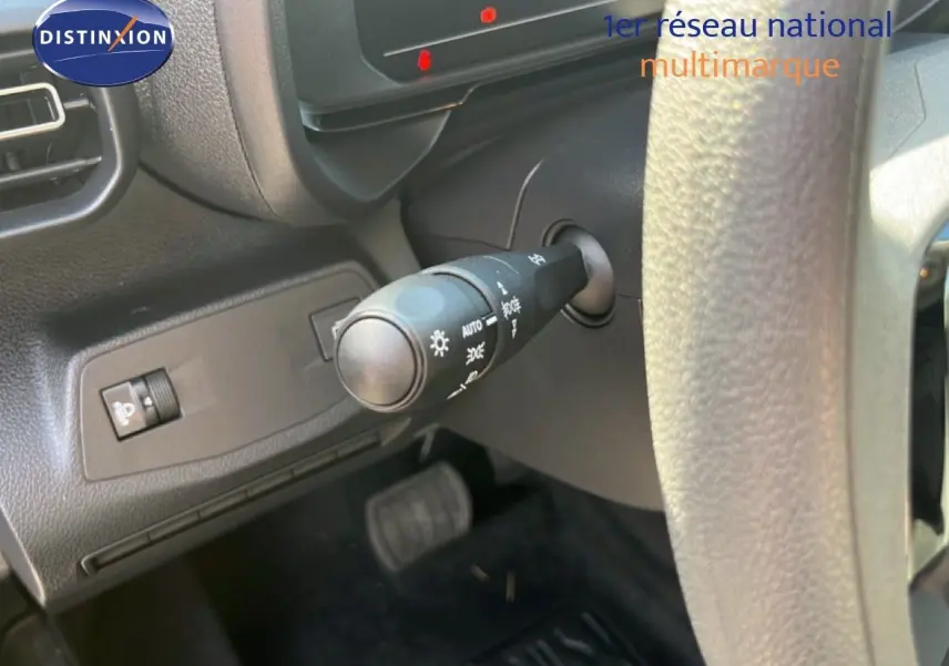 Gros plan sur la commande des phares à gauche du volant dans l’habitacle noir du Citroën Berlingo 2025.