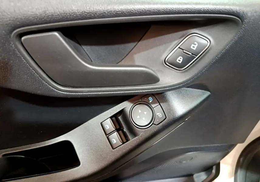 Gros plan sur la porte côté conducteur de la Ford Fiesta blanche, montrant la poignée, les commandes de vitres et de verrouillage.
