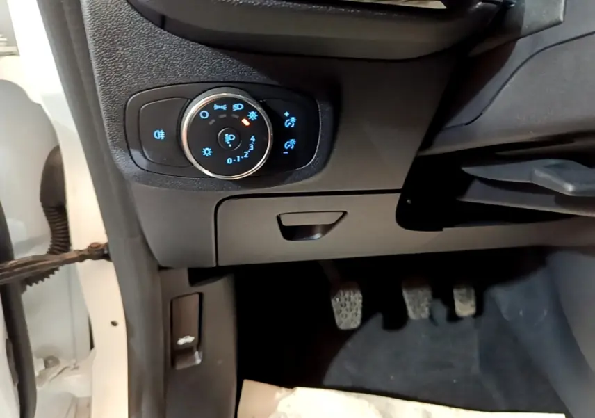 Détail du tableau de bord côté gauche avec commande d’éclairage et pédales dans une Ford Fiesta blanche 2022.