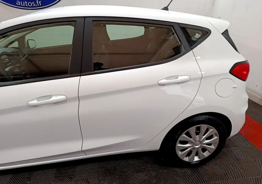 Vue latérale droite d'une Ford Fiesta blanche 2022, mettant en valeur les portières et la roue arrière.