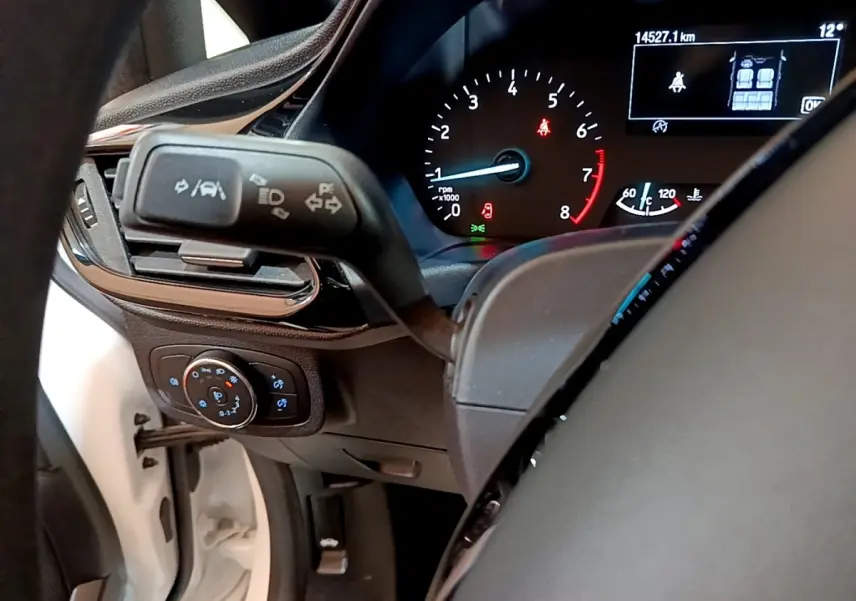 Vue intérieure du tableau de bord de la Ford Fiesta blanche, avec affichage numérique et commandes au volant visibles.