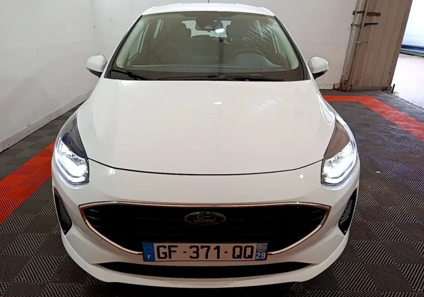 Vue avant d'une Ford Fiesta blanche 2022 avec phares LED allumés dans un garage.