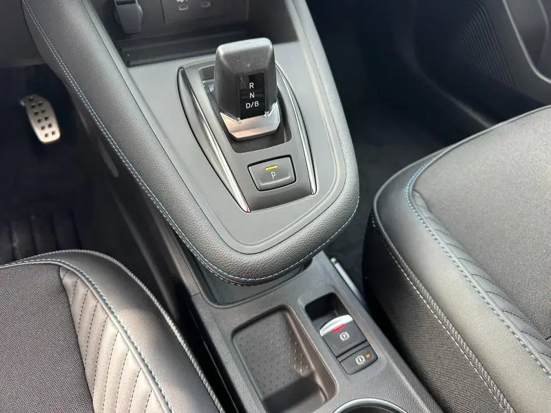 Vue rapprochée de la console centrale du Renault Captur 2026, avec levier de vitesse automatique et sellerie noire à surpiqûres bleues.