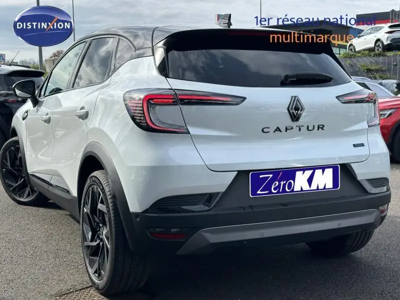 Vue 3/4 arrière droite du Renault Captur blanc nacré avec toit noir et jantes noires distinctives.