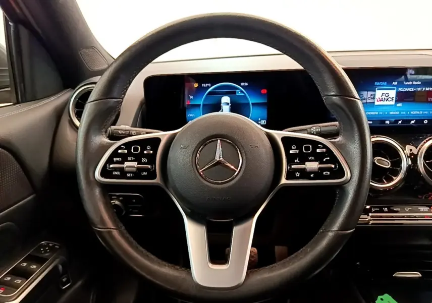 Vue intérieure centrée sur le volant cuir et alu d’un Mercedes GLB 200 d Business Line avec tableau de bord digital.