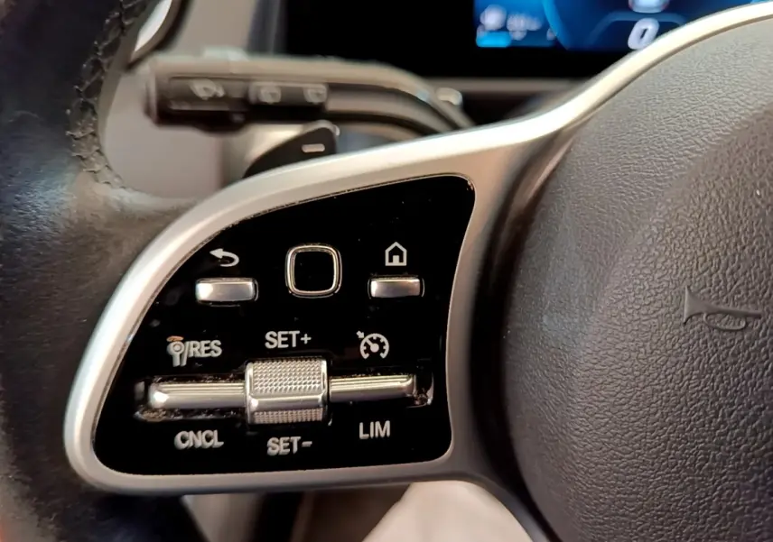 Gros plan sur les commandes multifonctions en alu et noir du volant côté gauche du Mercedes GLB 200 d Business Line gris foncé.