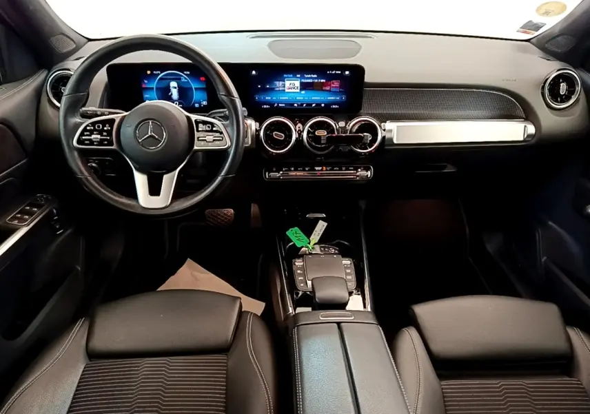 Vue intérieure avant du tableau de bord et volant cuir noir du Mercedes GLB 200 d Business Line avec écran tactile et commandes au volant.