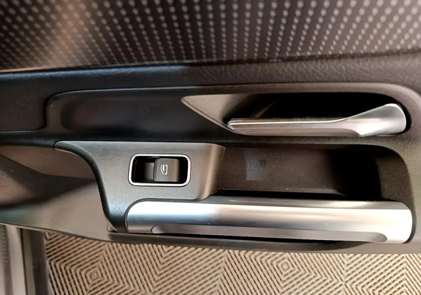 Gros plan sur la poignée intérieure côté gauche avec bouton de verrouillage, finition argent et noir du Mercedes GLB 200 d.