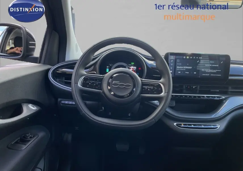 Vue intérieure frontale du tableau de bord et volant noir cuir du FIAT 500 électrique 2023 avec écran tactile et commandes intégrées.