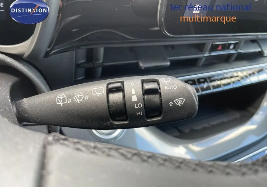 Gros plan sur la commande d’essuie-glace à gauche du volant dans l’habitacle noir de la Fiat 500 électrique 2023.