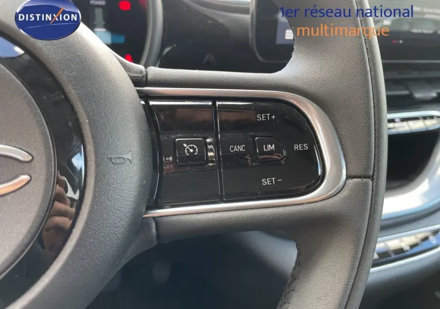 Gros plan sur les commandes de régulateur de vitesse au volant cuir noir de la FIAT 500 électrique 2023.
