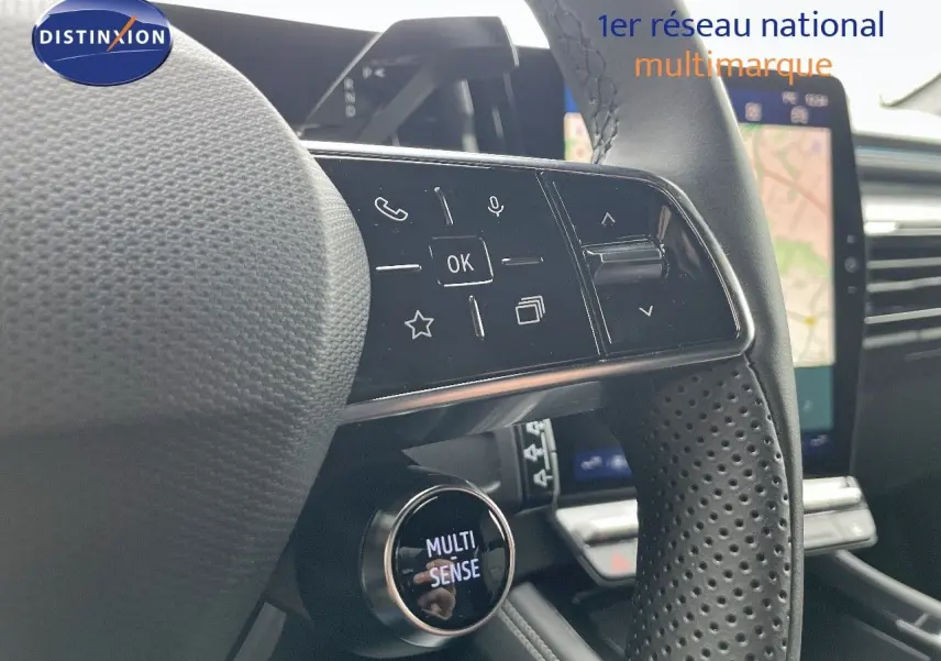 Gros plan sur le volant noir perforé du Renault Austral 2025 avec commandes intégrées et bouton Multi-Sense.