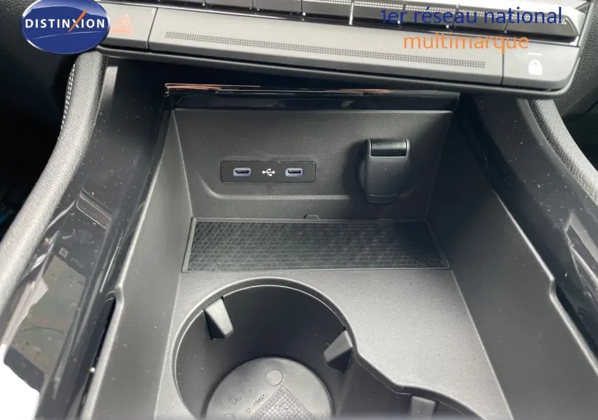 Gros plan sur la console centrale noire du Renault Austral E-Tech 2025, avec ports USB et porte-gobelet intégré.