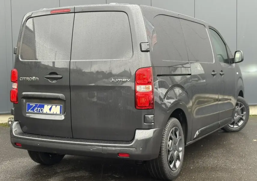 Vue 3/4 arrière droite d'un Citroën Jumpy gris titane avec portes arrière battantes et jantes noires.