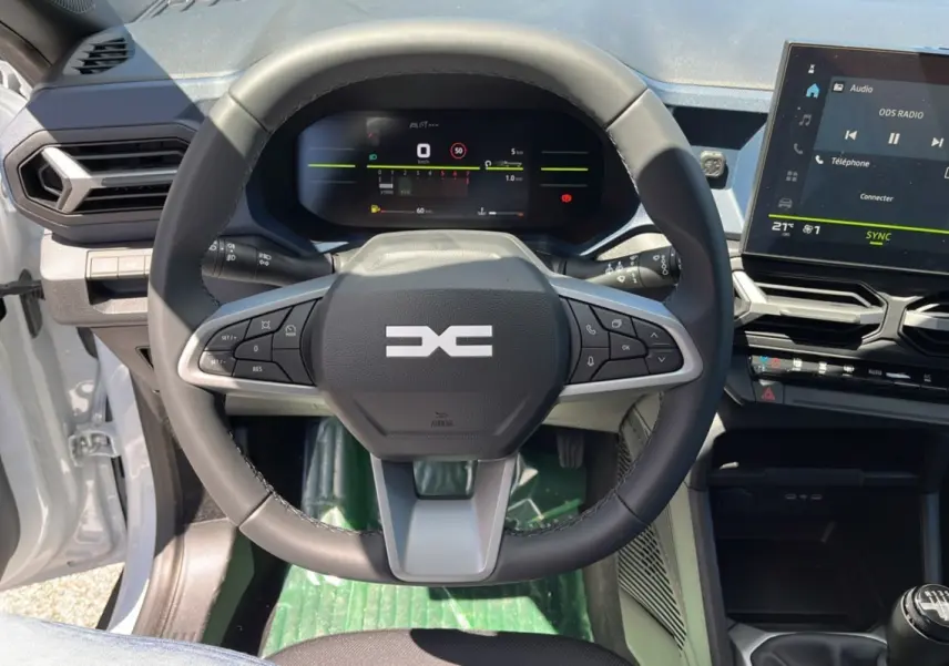 Vue rapprochée du volant cuir noir et du tableau de bord numérique du Dacia Bigster blanc glacier 2025.