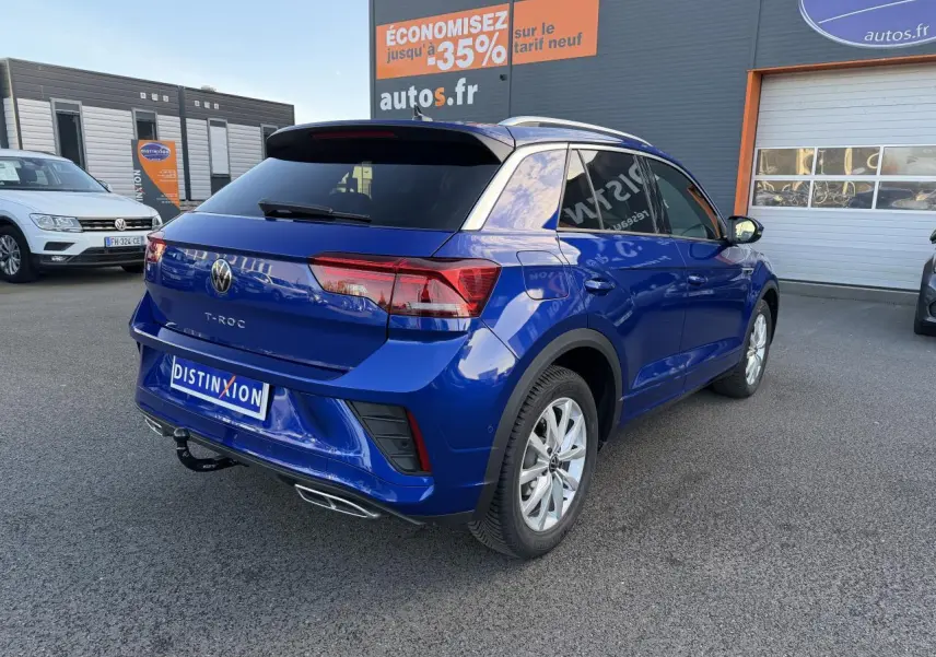 Volkswagen T-Roc bleu lapiz métallisé vu en 3/4 arrière droit avec attelage amovible et jantes alliage gris galvanisé.