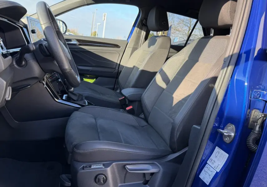 Vue intérieure côté conducteur du Volkswagen T-Roc Bleu Lapiz 2025, montrant les sièges avant et le volant sport R-Line.